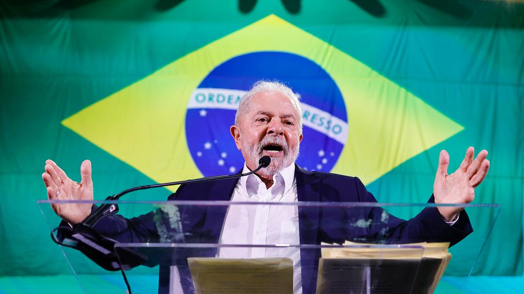 O presidente Lula gesticula e discursa em frente a uma bandeira do Brasil