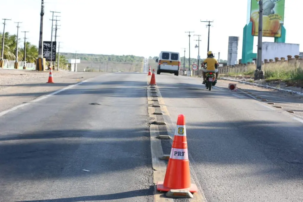Rodovia federal com cones da PRF. Um transporte de passageiros passa na frente