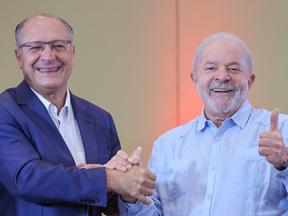 Geraldo Alckmin e Lula. Os dois estão sorrindo e de mãos dadas.