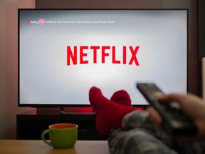 Televisão com logotipo da Netflix e pessoa assistindo com os pés para cima em uma confortável casa