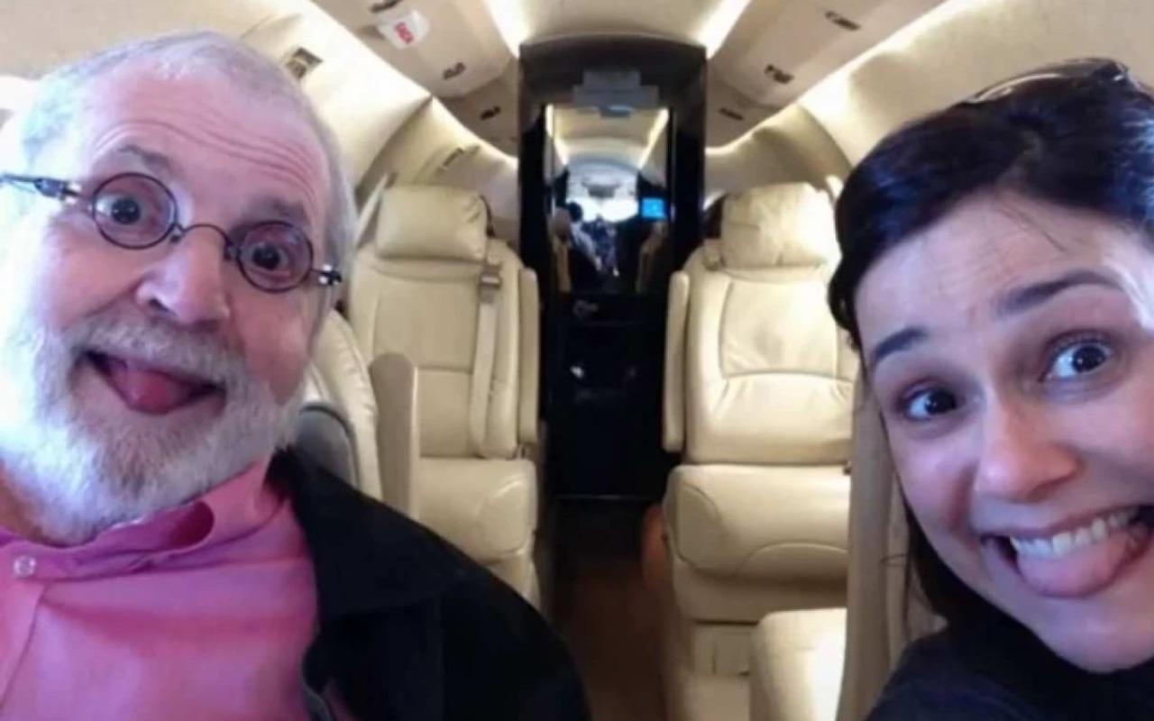 Jô Soares e Flávia Pedras em avião. Eles estão fazendo careta com a língua para fora