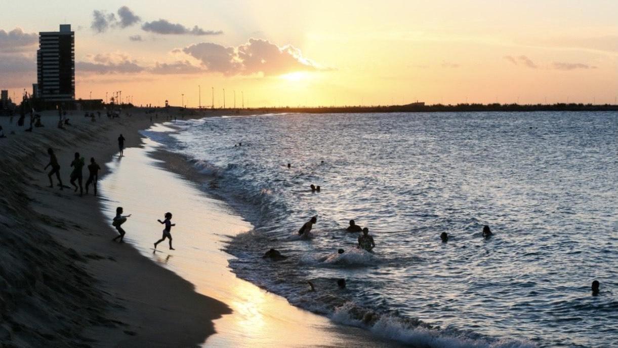 Banhistas se divertem na orla de Fortaleza ao fim de tarde.