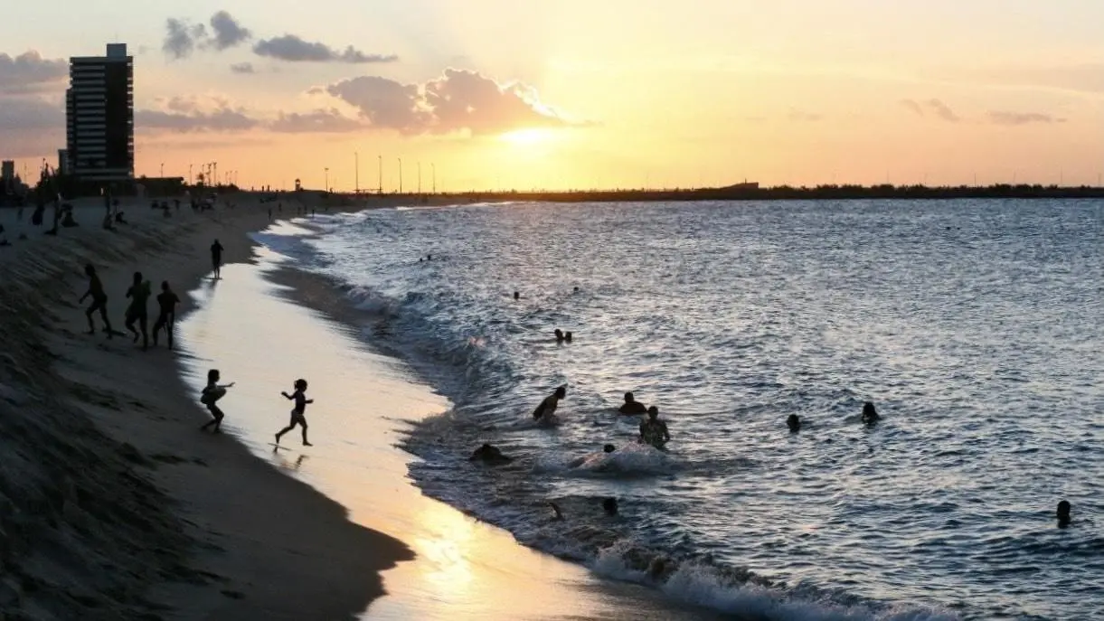 Banhistas se divertem na orla de Fortaleza ao fim de tarde.