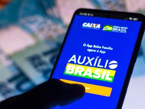 Mão segura celular aberto no aplicativo do Auxílio Brasil, da Caixa