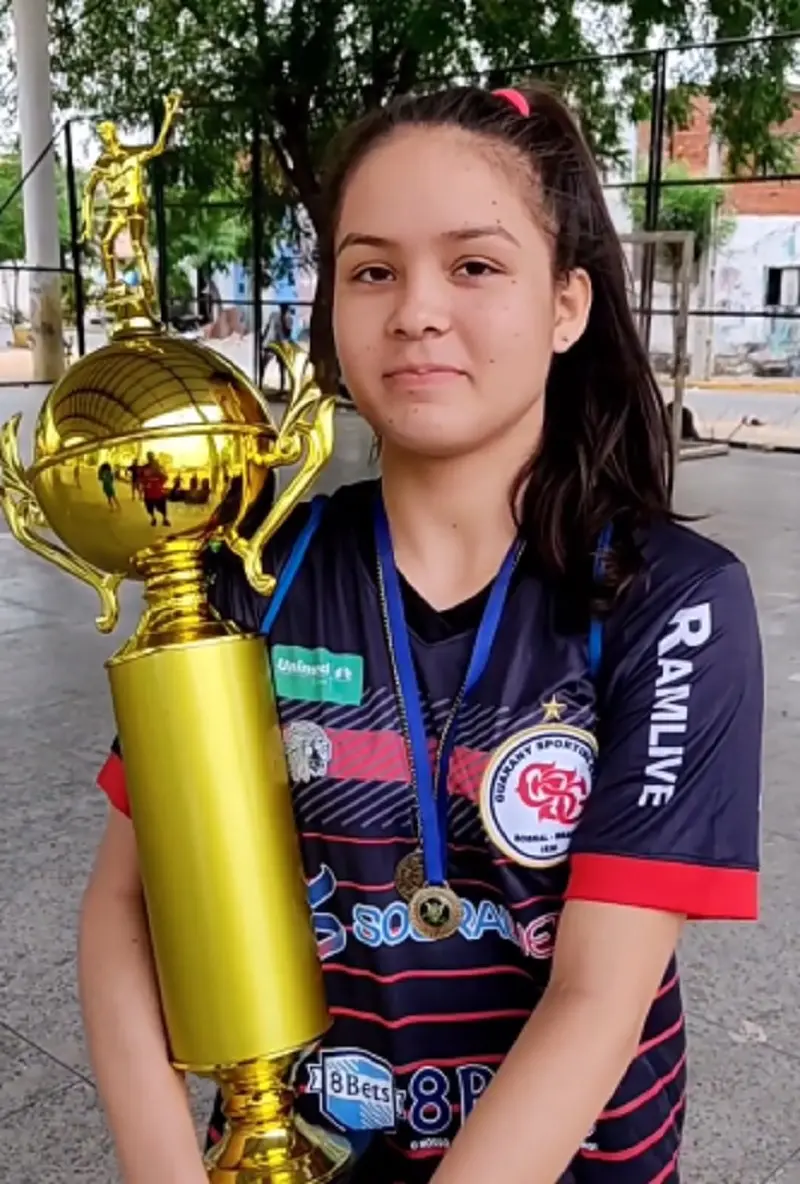 Imagem mostra menina segurando um trofeu