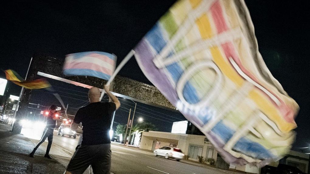 Manifestante segurando bandeira com as cores da bandeira LGBTQIA+ para incentivar pessoas a votarem nas eleições nos Estados Unidos