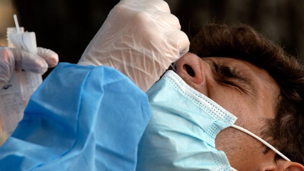 Enfermeiro aplica teste SWAB em paciente usando máscara azul