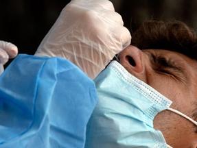 Enfermeiro aplica teste SWAB em paciente usando máscara azul