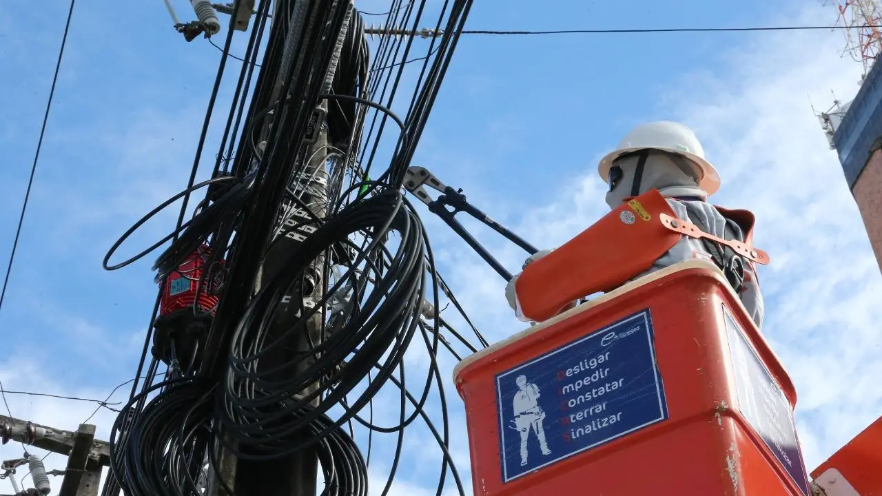 Técnico segura fios em poste