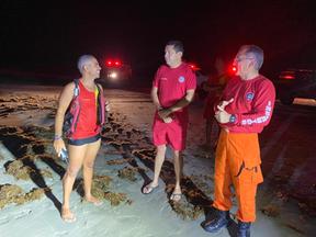 bombeiros conversando à beira-mar durante resgate
