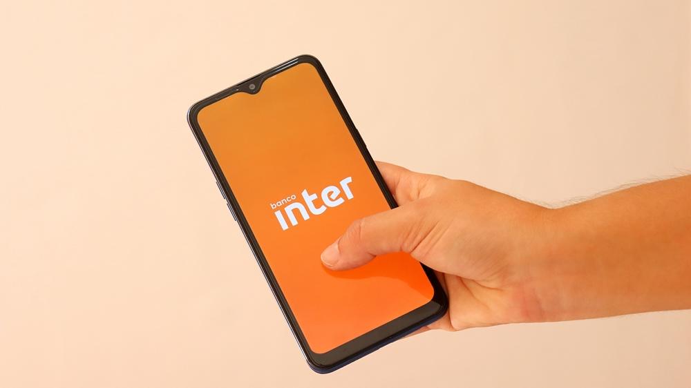 Mão segura celular aberto no aplicativo do Banco Inter