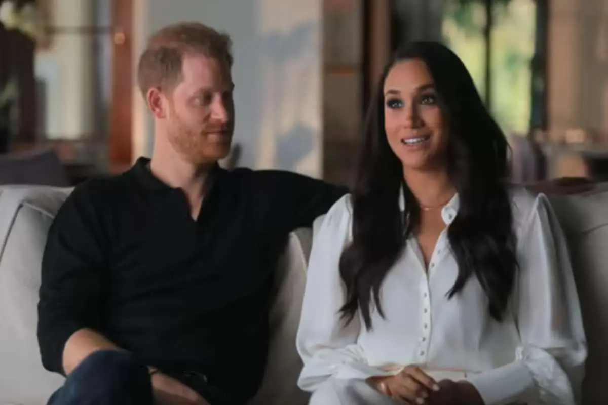 Harry e Meghan sentados lado a lado dando entrevista