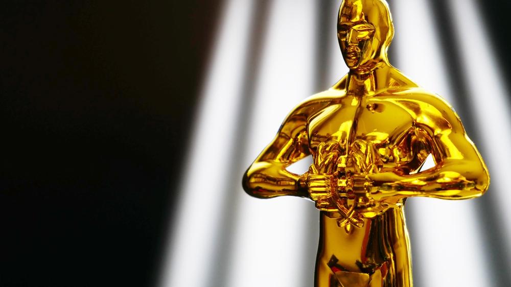 Estatueta de ouro do Oscar em fundo escuro com luz prateada