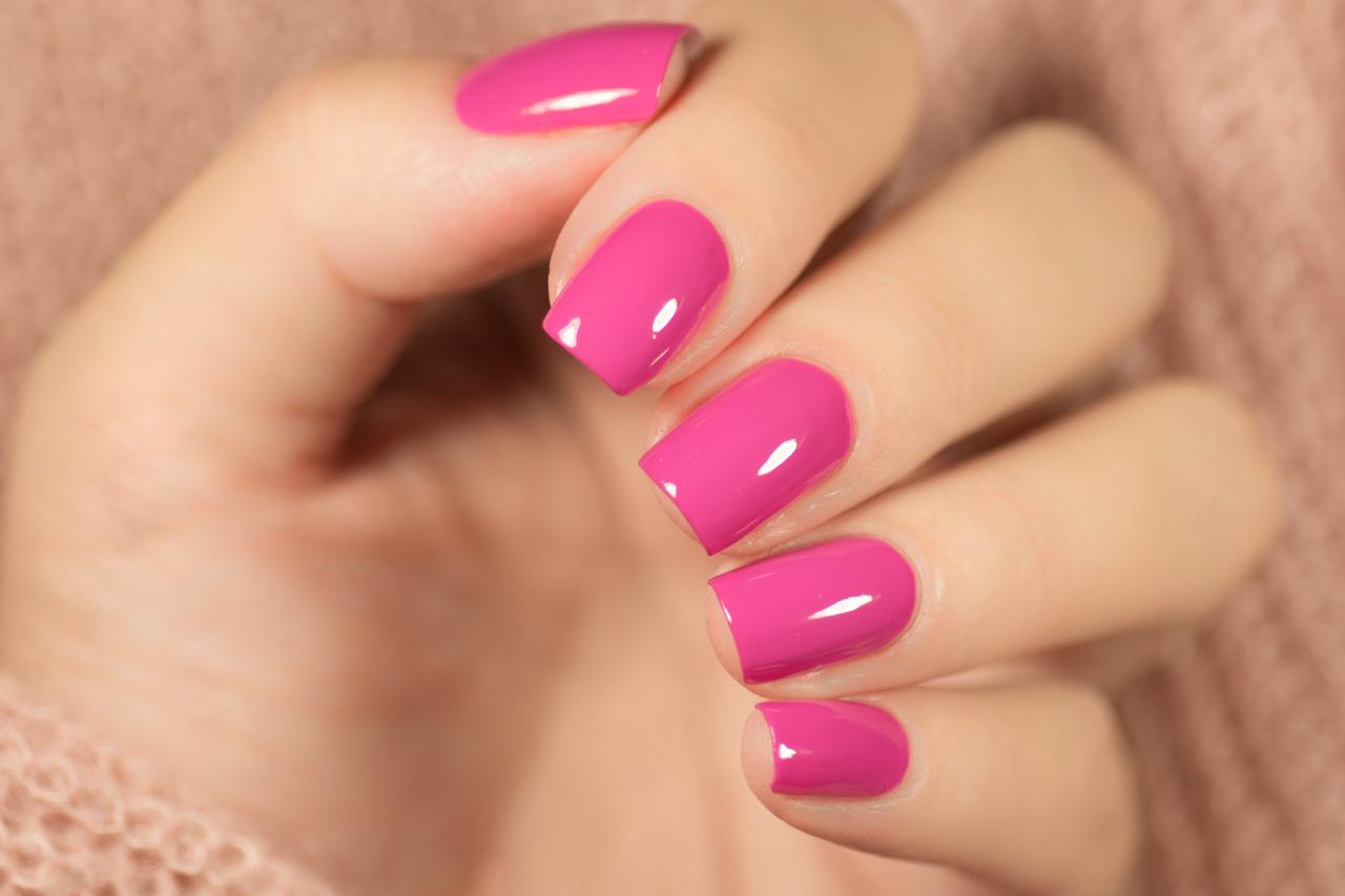 Mão com unhas pintadas de rosa vibrante
