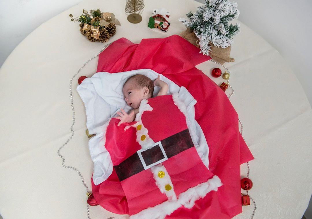 Paciente recém-nascido, internado na Unidade de Terapia Intensiva Neonatal (UTI Neo) do do Hospital Geral Dr. Waldemar Alcântara (HGWA), posa usando roupas de temática natalina