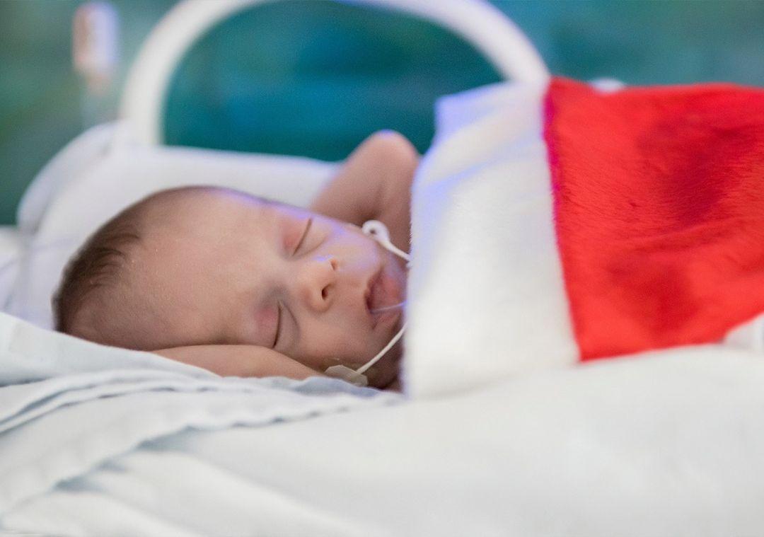 Paciente recém-nascido, internado na Unidade de Terapia Intensiva Neonatal (UTI Neo) do Hospital Geral Dr. Waldemar Alcântara (HGWA), posa usando roupas de temática natalina