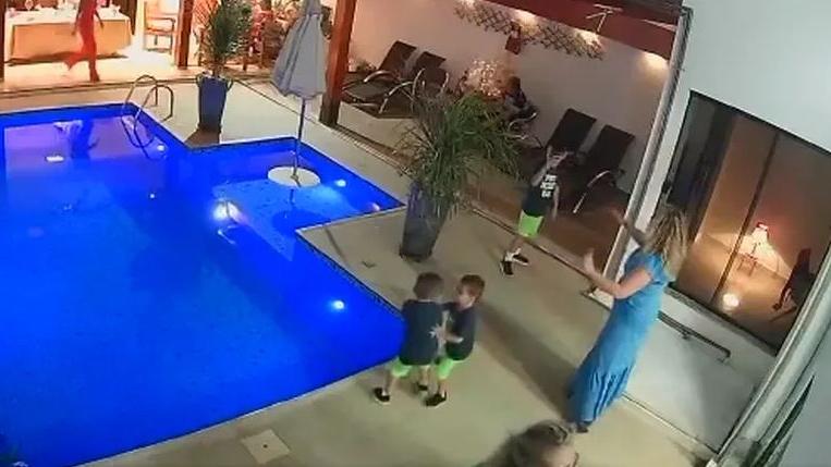 Frame de câmera de segurança onde criança empurra outra em piscina