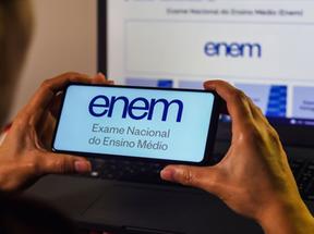 Pessoa segurando celular mostrando a logomarca do Enem