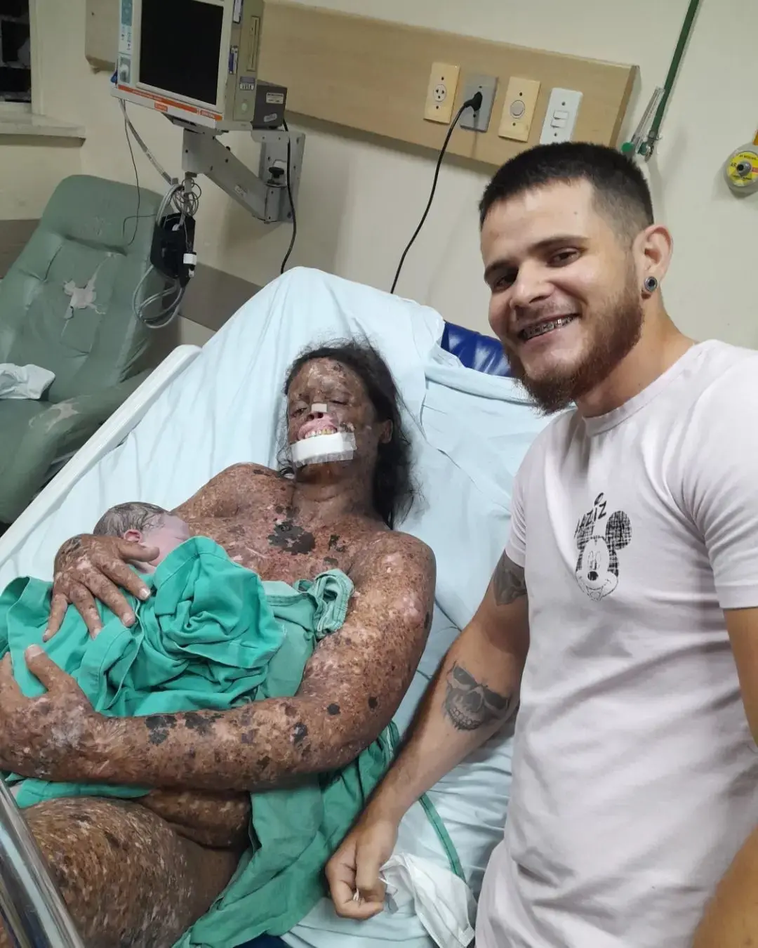 influenciadora karine sousa com bebê, deitada em leito de hospital, com homem sorrindo ao lado