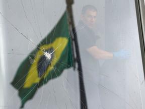 Vidraça quebrada com a bandeira do Brasil ao fundo