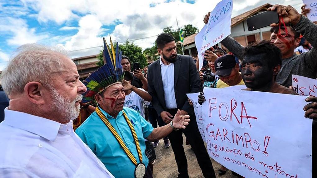 presidente lula conversa com indígena que segura cartaz em que se destacam as palavras fora garimpo