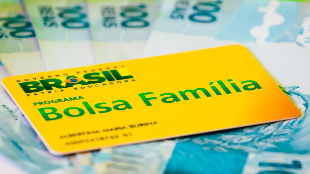 Cartão do Bolsa Família sobre cédulas de R$ 100