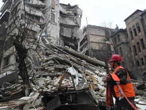 Um membro de uma equipe de resgate caminha com suas ferramentas em direção a um prédio que desabou após um terremoto na cidade síria de Aleppo, em 6 de fevereiro de 2023