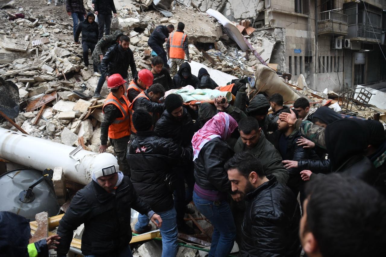 Membros da defesa civil síria carregam uma mulher ferida após resgatá-la dos escombros de um prédio que desabou após um terremoto na Aleppo controlada pelo governo em 6 de fevereiro de 2023
