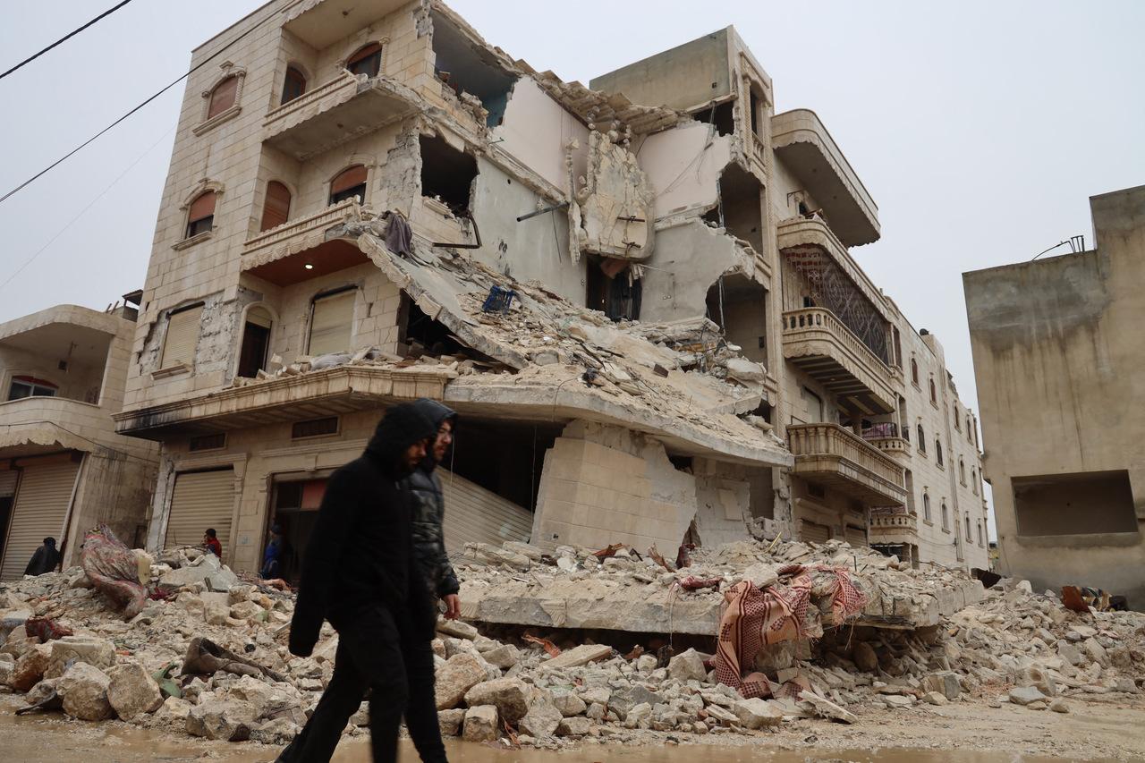Dois homens passam por um prédio fortemente danificado após um terremoto na cidade de Sarmada, no interior da província de Idlib, no noroeste da Síria, no início de 6 de fevereiro de 2023