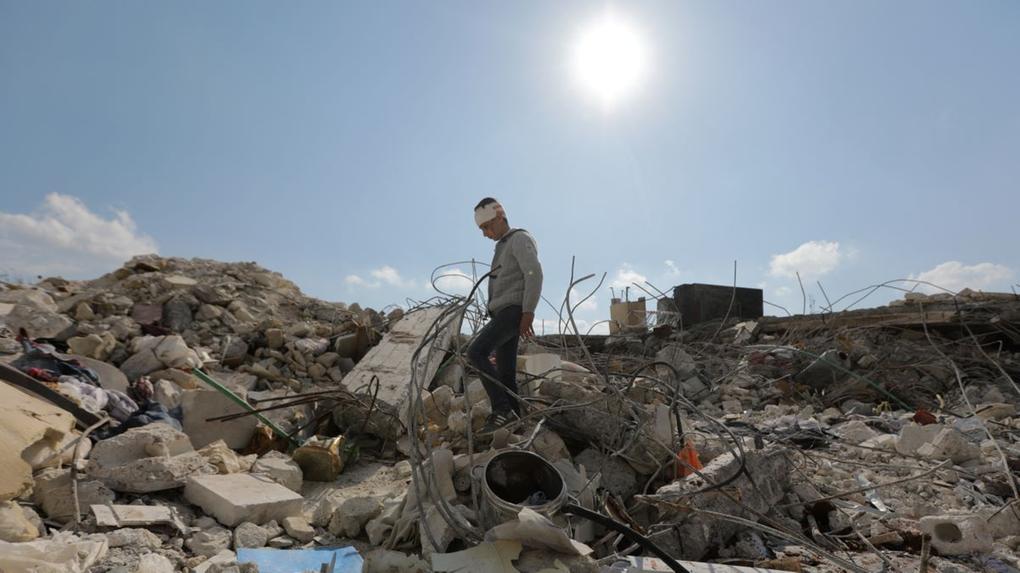 imagens de destroços do terremoto na turquia, com uma pessoa em cima  dos escombros
