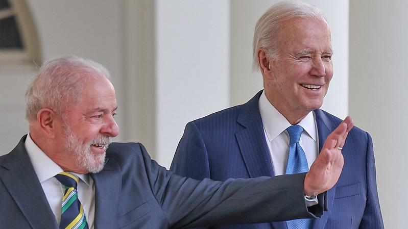 Lula e Biden são idosos brancos e de cabelos brancos. Lula é mais baixo e usa barba