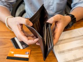 Mão abre carteira vazia em cima de mesa com cartões de crédito