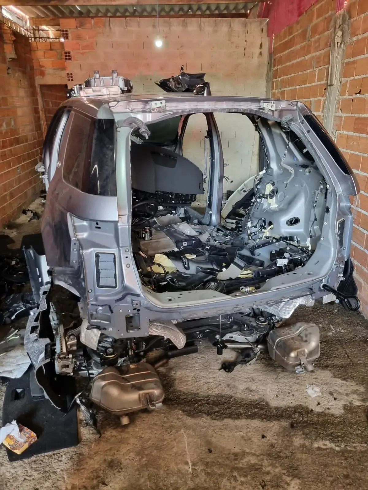 Carro desmontado, quase sem peças, dentro de uma garagem