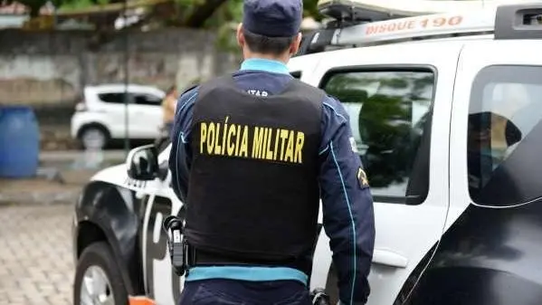 Policial militar de costas em frente a viatura