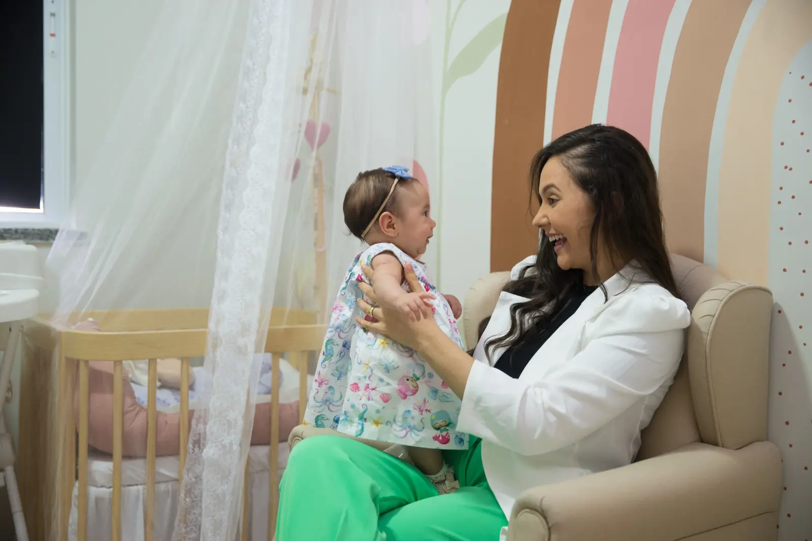 Mãe carrega filho no colo e ri enquanto olha para a bebê