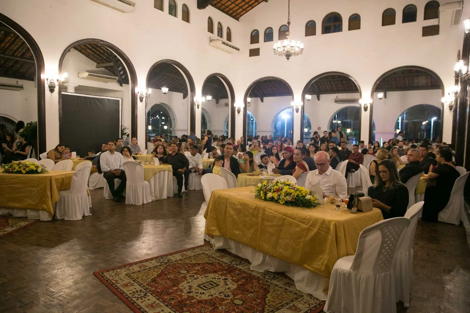 Imagem mostra mesas e cadeiras em um salão de festas
