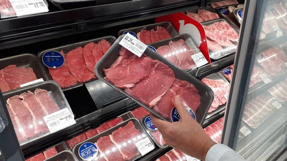 Pessoa pega bandeja de carne em supermercado