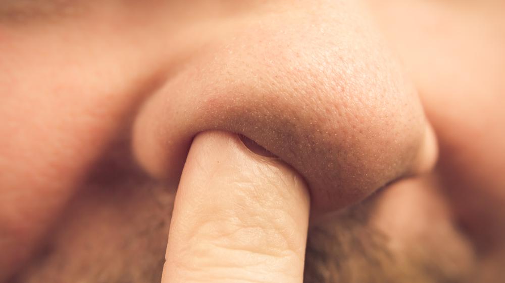 Homem insere dedo no nariz