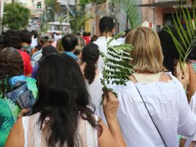 Mulher segura ramo em procissão em Fortaleza
