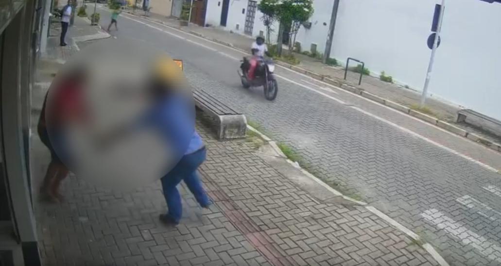 Imagem de uma rua no Bom Jardim. Na calçada, dois homens aparecem brigando e um outro aparece em uma moto.