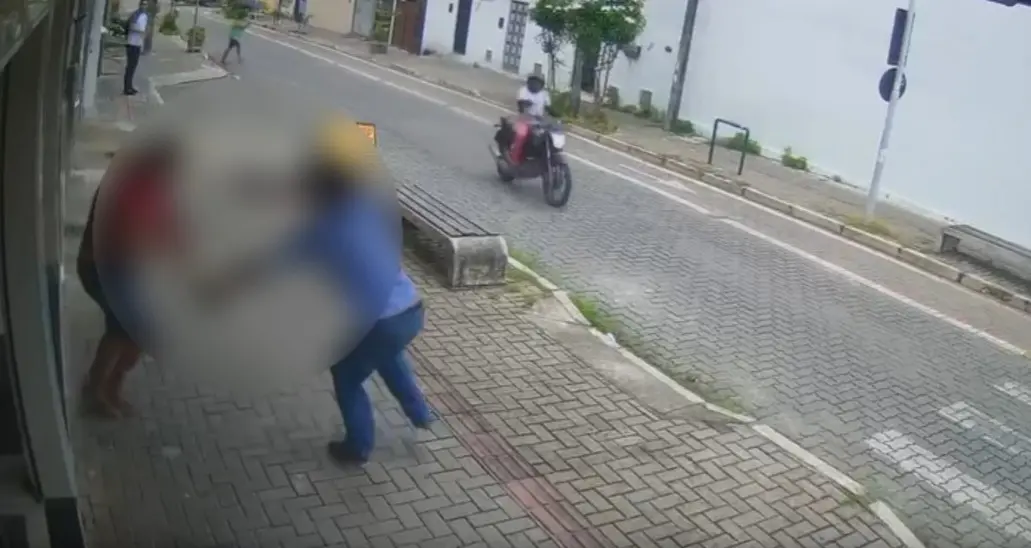 Imagem de uma rua no Bom Jardim. Na calçada, dois homens aparecem brigando e um outro aparece em uma moto.