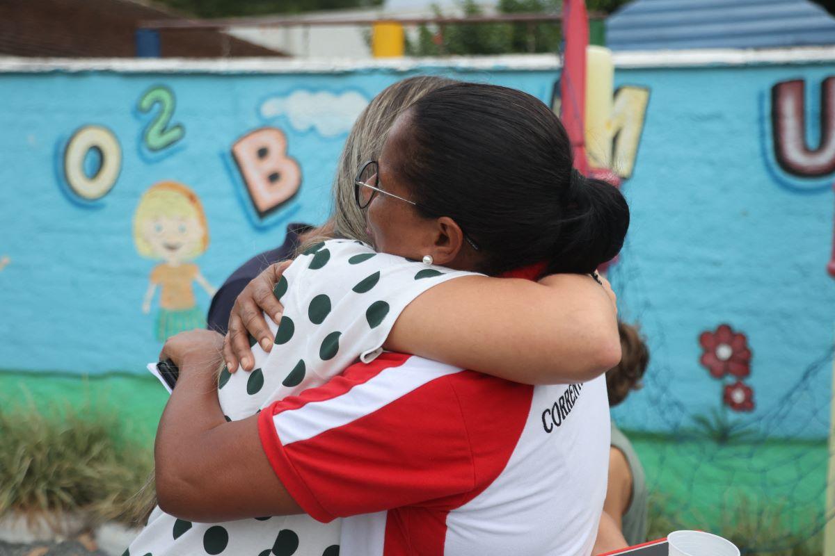 Mulheres se abraçando em frente a creche que foi alvo de ataque que deixou crianças mortas