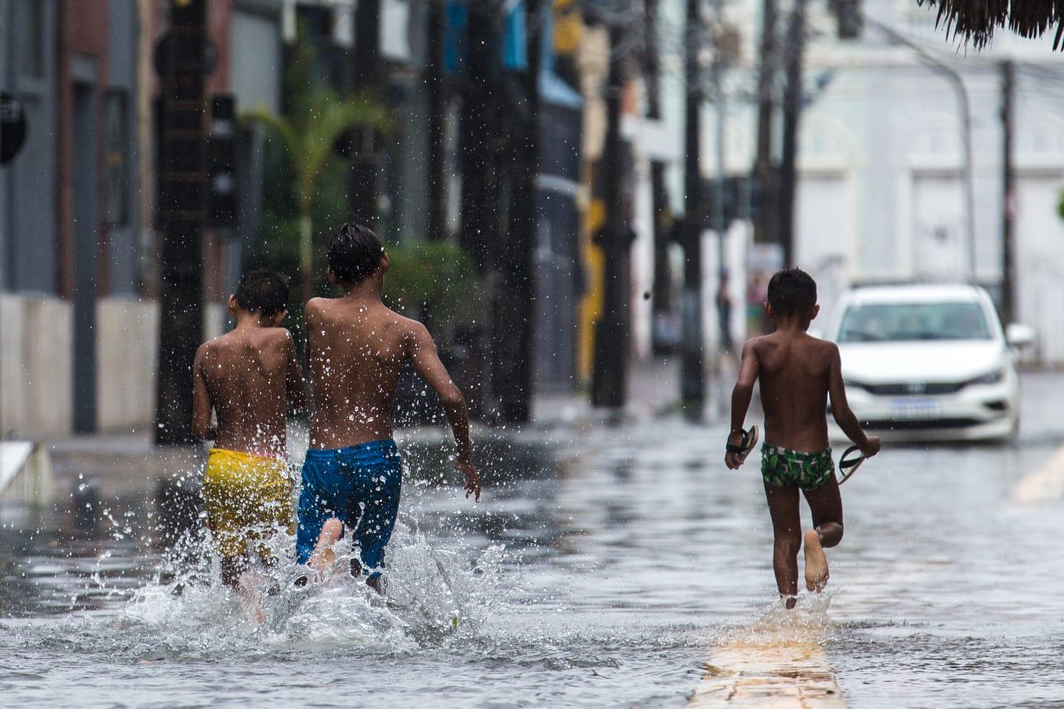 crianças brincando em avenida alagada pela chuva em fortaleza