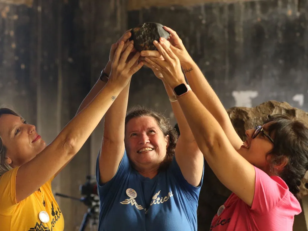 As pesquisadoras Amanda Tosi, Maria Elizabeth Zucolotto e Diana Andrade apresentam o meteorito Santa Filomena