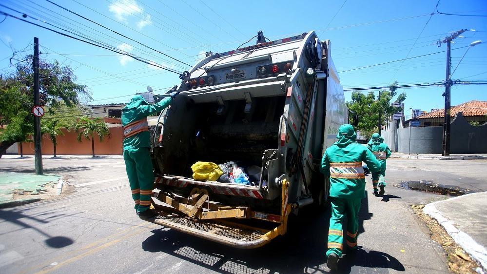 Profissionais da limpeza em caminhão passando por ruas de Fortaleza