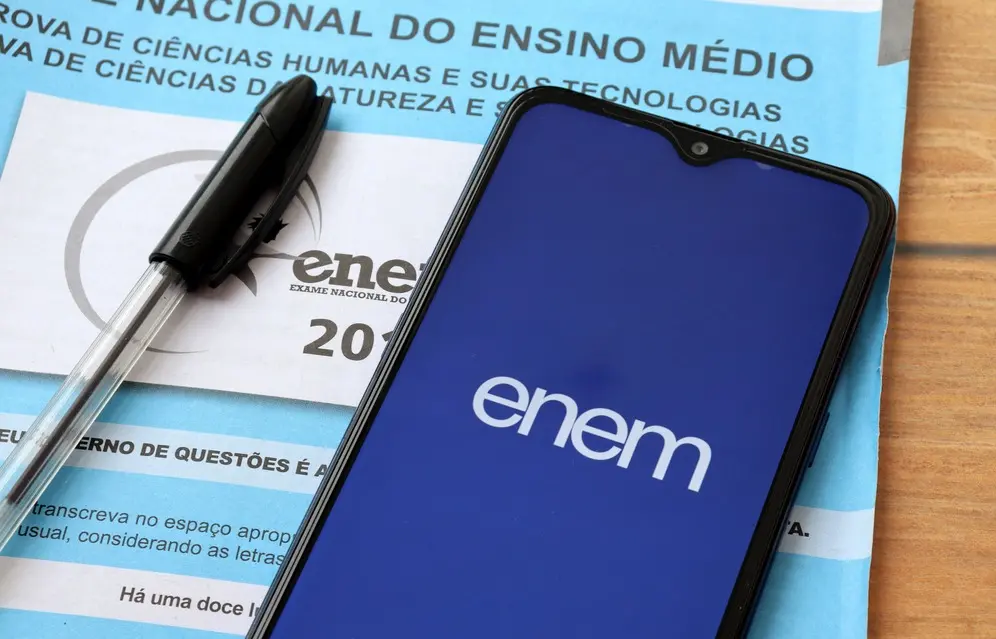 Prova azul do Enem e um celular aberto no aplicativo do exame
