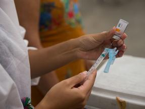 pessoa colocando vacina em seringa