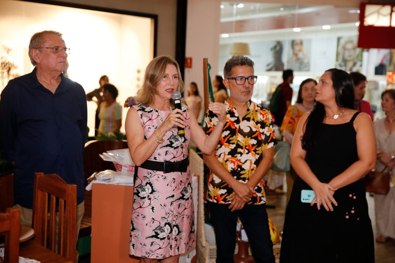Renata Jereissati, ao centro, gesticula enquanto discursa no lançamento da exposição do Render-CE, no Iguatemi. Ao seu lado, de camisa colorida e óculos de armação grossa, o artista Mário Sanders.