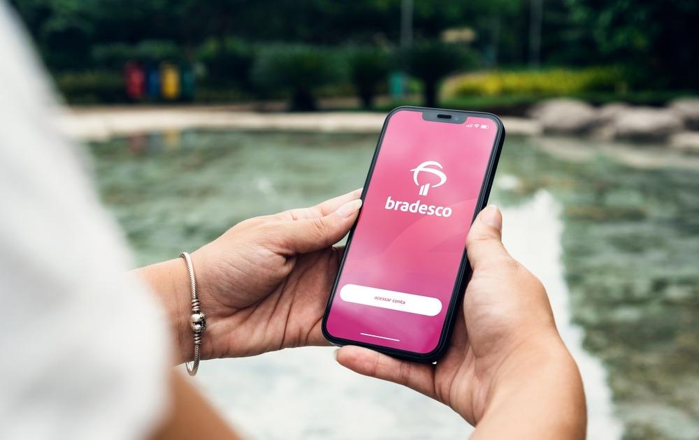 Mão feminina segura celular aberto no aplicativo do banco Bradesco
