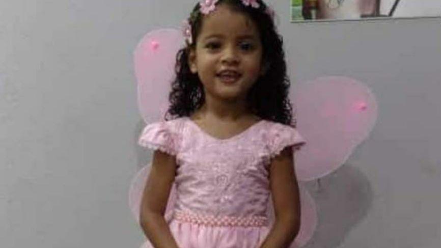 A vítima é uma menina negra, de cinco anos de idade. Ela está vestida com um vestido rosa, com asas de borboleta.